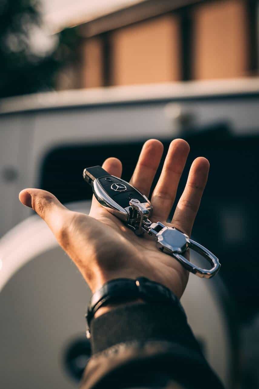Male hand outstreched, holding a Mercedes Car keyfob on a silver keyring