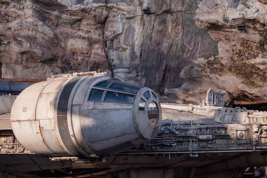 Side of the Millenium Falcon spaceship in front of a rocky cliffside