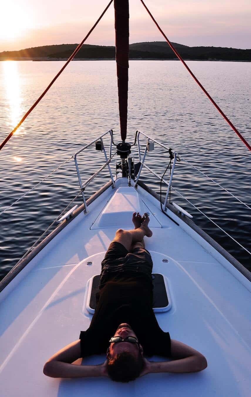 Man lay down at the front of a white yacht on the ocean