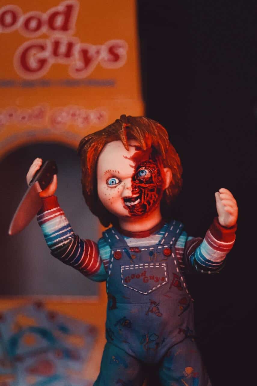 Red haired childs doll wearing dunagrees and weidling a knife, half his face missing