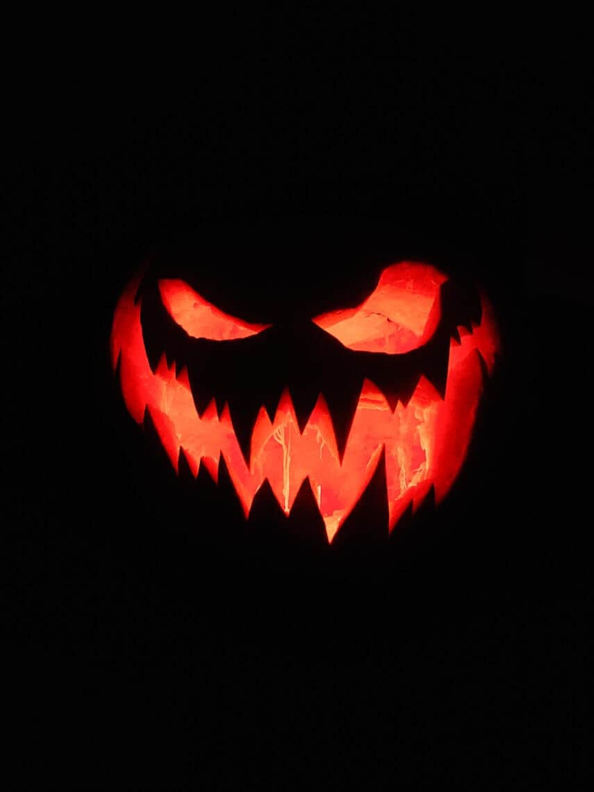 Scary looking jack o lantern with jagged teeth lit up from the inside